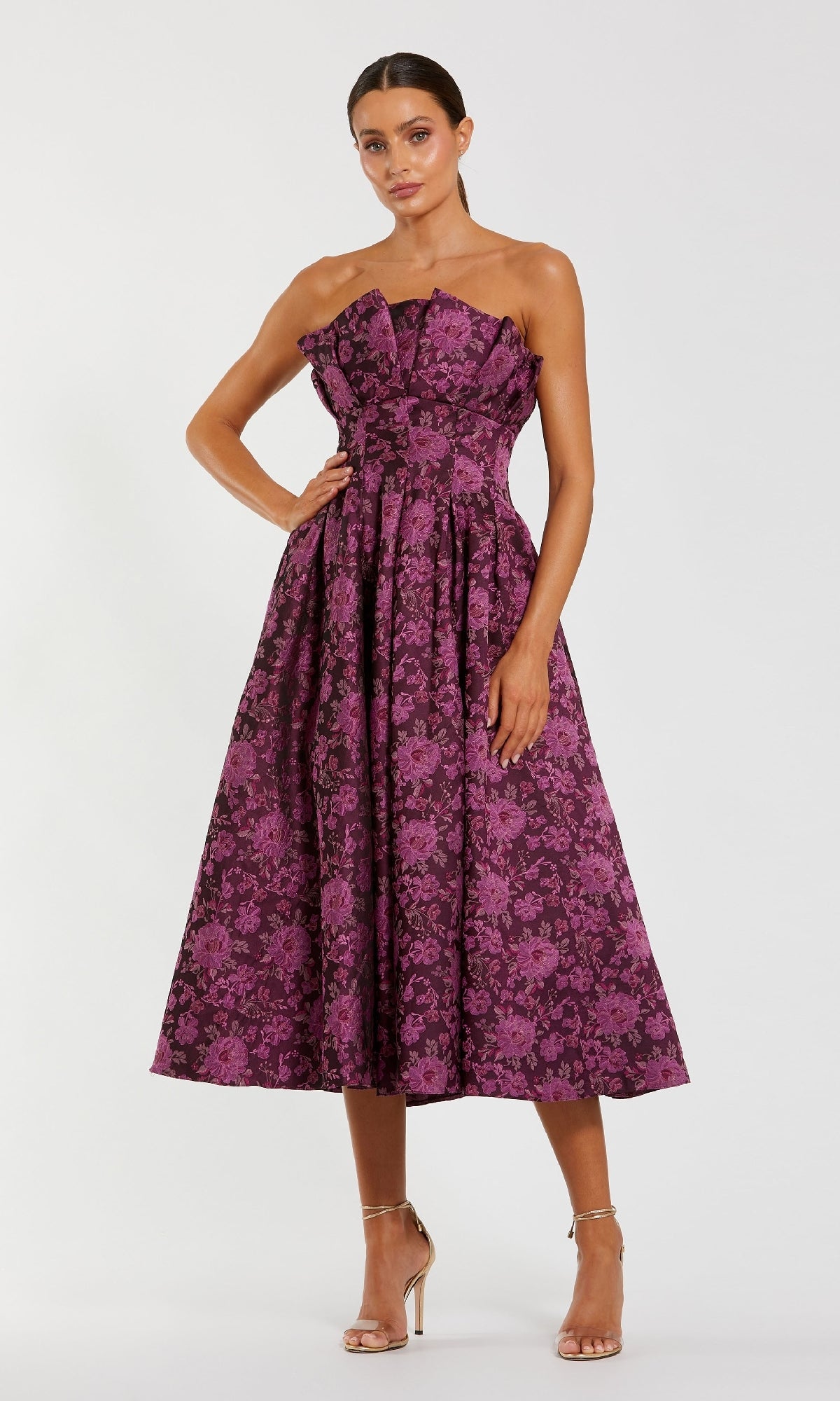 A woman wears the Mac Duggal 56159 Strapless Wedding Guest Dress, featuring a floral-print fitted bodice and flared midi skirt, paired with strappy high-heeled sandals—an elegant, chic choice for attending weddings.